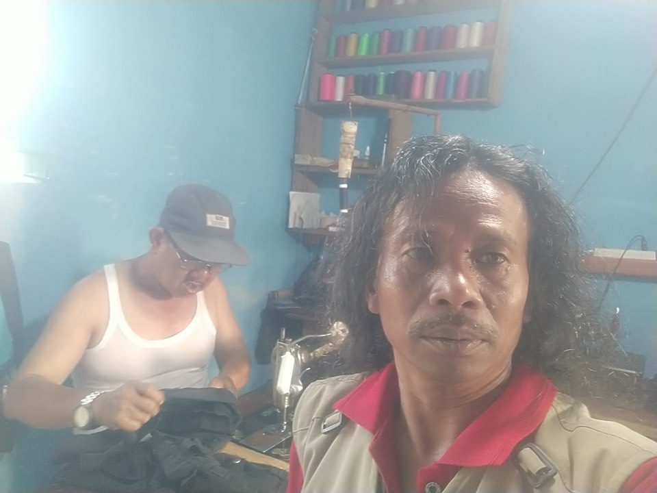 Darsono sedang melayani pelanggan di tempat usaha jasa jahit, servis tas, dan vermak pakaian di Desa Karangmangu, Kabupaten Kuningan.